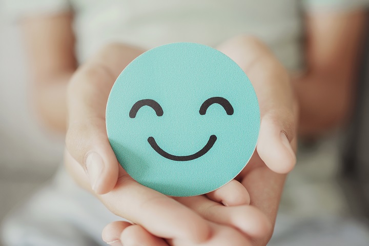 green smiley face being held in a pair of hands showing work-life balance