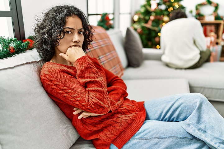 Unhappy woman on her own sitting on sofa after a relationship breakup